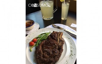 Fotografía de platillo de carne y verduras servido en mesa y acompañado de sopa y jarra de limonada